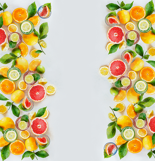 Frame of various colorful citrus fruits: lemon, lime, orange and grapefruit with green leaves and glasses of refreshing lemonade drinks on white background, top view. Healthy lifestyle. Layout.