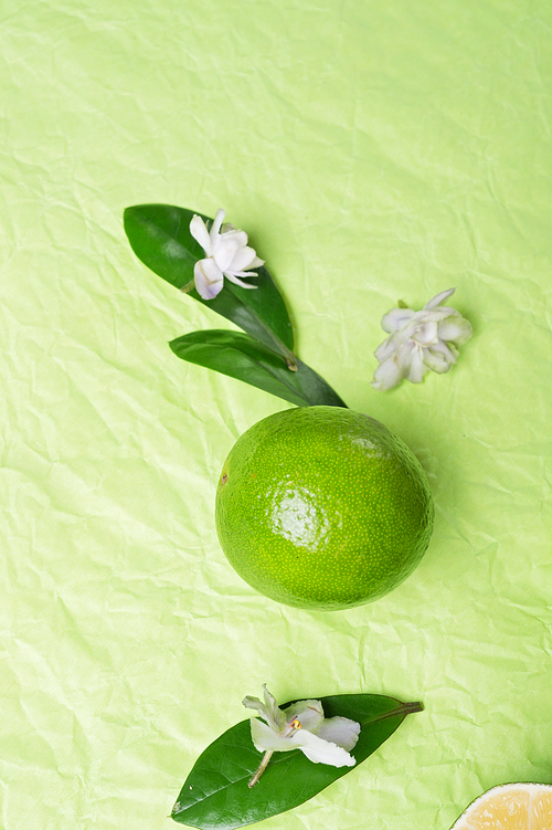 lime with leaves and flowers   on green background. flat lay. close up