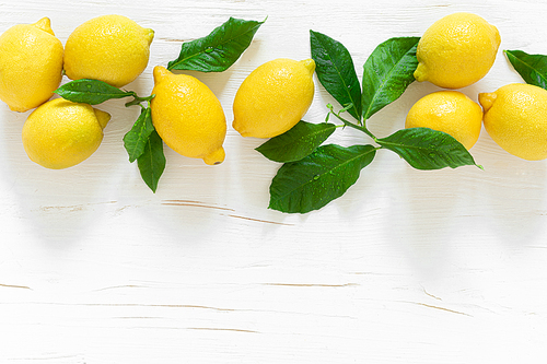 Fresh lemons with leaves on white wooden background,  summer lemonade ingredient, vitamin c concept, top view