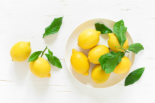Fresh lemons with leaves on white wooden background,  summer lemonade ingredient, vitamin c concept, top view