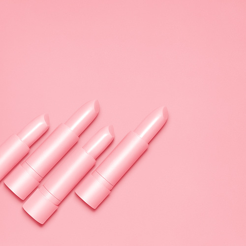 Creative still life of pink open lipsticks for makeup on pink background.