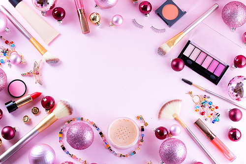 Festive make up products on pink background, flat lay frame with copy space