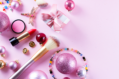 Festive make up products on pink background with copy space
