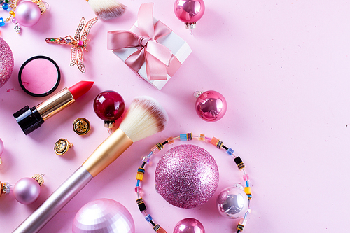 Festive make up products on pink background, top view border with copy space