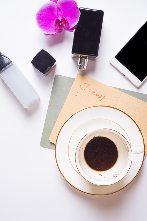 cup of coffee with diary and perfume around white background. life style flat lay
