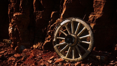 old wooden cart wheel on stone rocks