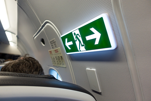Aircraft emergency exit sign and door on board passenger airplane