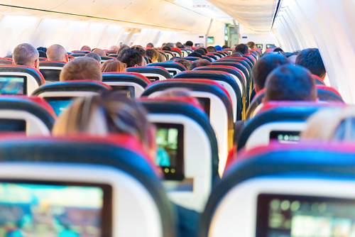 People flying sitting in plane interior with multimedia screens