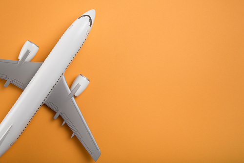 Airplane model view from above on orange paper background. Space for text.