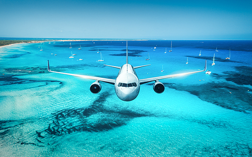 Airplane is flying over islands and sea at sunrise in summer. Landscape with white passenger airplane, seashore, boats, sky and azure water. White passenger aircraft. Travel and resort. Aerial view