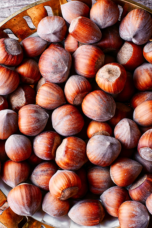 Fruits of hazelnut in the copper bowl and scattered near.Top view