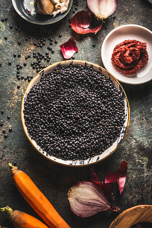 Close up black lentils in bowl with ingredients for delicious cooking.  Top view. Copy space. Healthy food. Protein rich vegan foods. Plant based protein  source