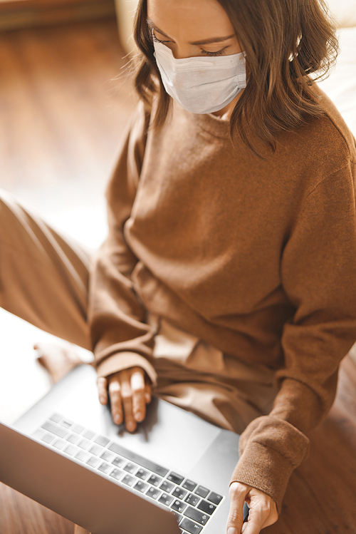 Lifestyle portrait of young lady working at notebook with mask. Woman concept for alternative office freelance. Stay home. Coronavirus. Quarantine. Online training education and freelance work. Coronavirus pandemic in the world