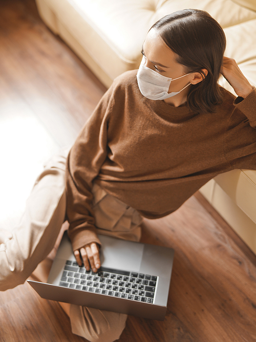Lifestyle portrait of young lady working at notebook with mask. Woman concept for alternative office freelance. Stay home. Coronavirus. Quarantine. Online training education and freelance work. Coronavirus pandemic in the world