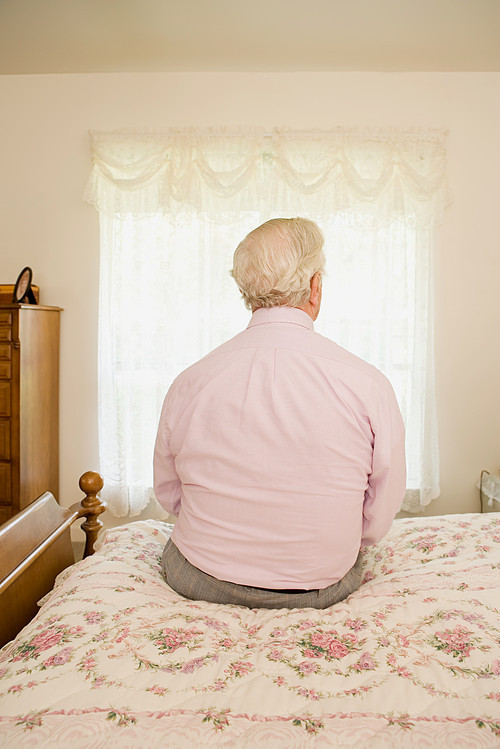 Elderly man sitting on bed