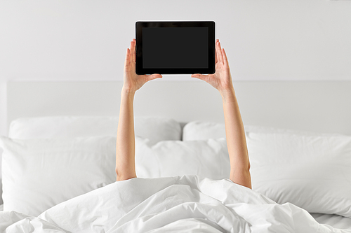 technology, comfort and morning concept - hands of young woman lying in bed with tablet pc computer at bedroom