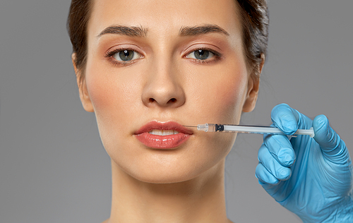 cosmetology, plastic surgery and beauty concept - beautiful young woman and hand with syringe making lifting injection over grey background and snow