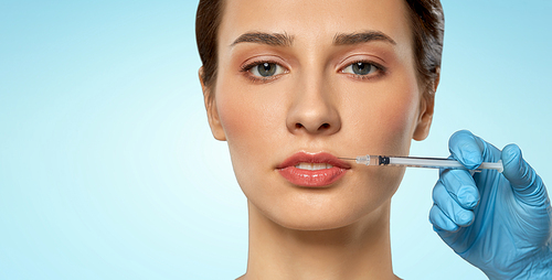 cosmetology, plastic surgery and beauty concept - beautiful young woman and hand with syringe making lifting injection over blue background