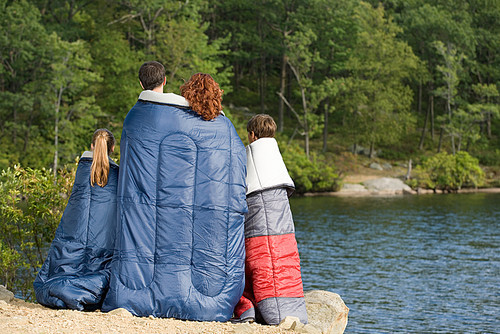 Family in sleeping bags by lake