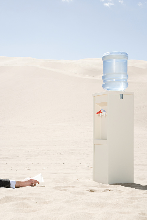 Person reaching for water cooler in desert