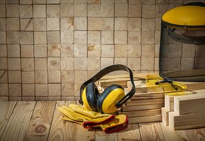 carpenter tools headphones gloves goggles and saw mask on wooden background