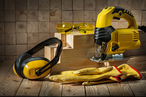 carpentry tools electric corded jigsaw gloves goggles earphones on wooden background