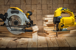 construction carpentry tools electric corded circular saw and jigsaw on wooden background