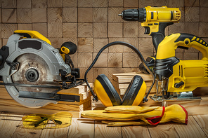 construction carpentry tools electric corded circular saw jigsaw cordless drill earphones gloves goggles on wooden background