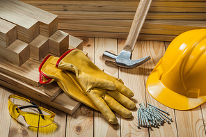 carpenter tools gloves hammer helmet nails goggles on wooden timber background