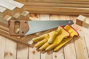handsaw and yellow working gloves on wooden timber materials