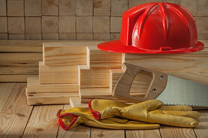 construction carpentry tools red helmet glaves and handsaw on wooden background