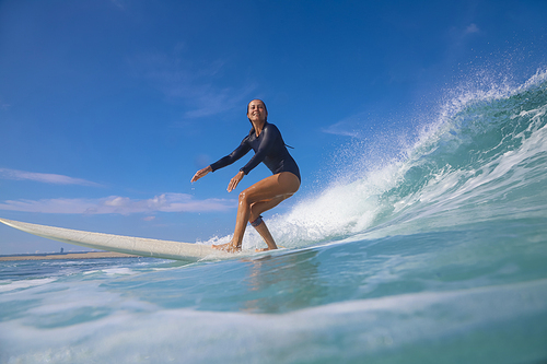 Female surfer on a blue wave at sunny day