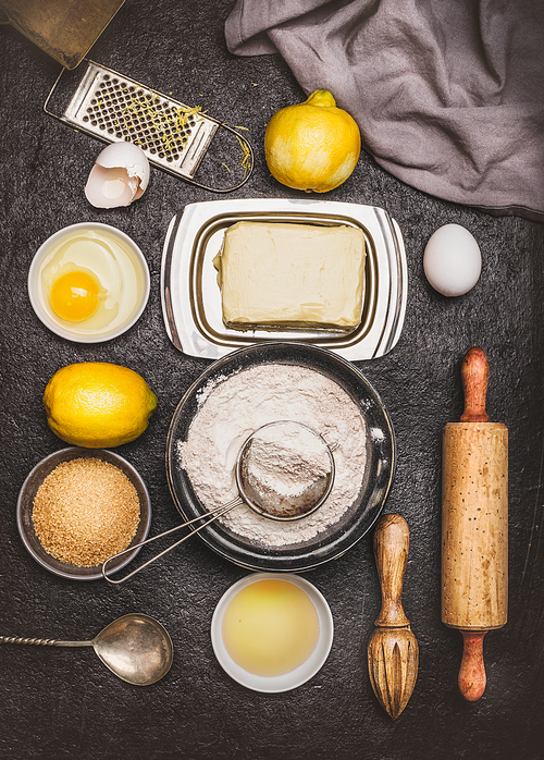 Bake ingredients and tools for lemon cookie or cake dough making on dark background, top view, flat lay