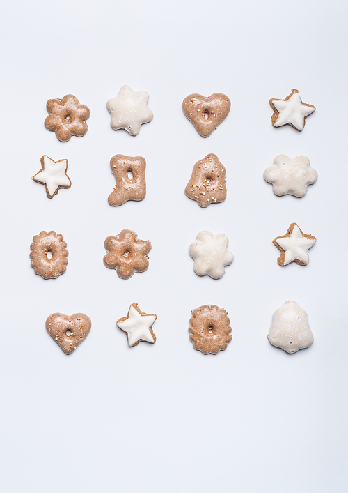 Christmas gingerbread layout on white desk background, top view. Flat lay with cookies in shape of star, heart and bell. Festive layout or pattern for greeting card
