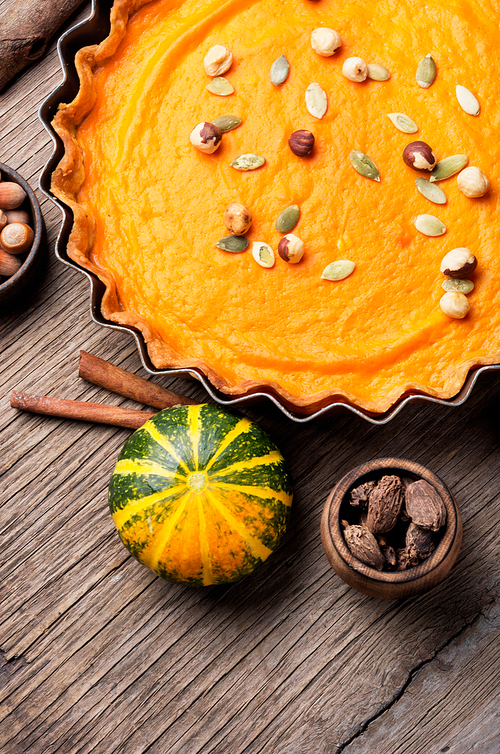 Pumpkin pie with nut and spice on rustic background.Thanksgiving pumpkin pies