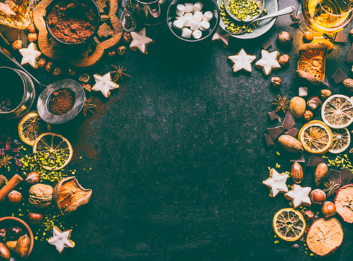 Christmas spices, chocolate and cookies background with ingredients for baking and sweet food: nuts, dried fruits, broken chocolate and spirits on dark background, top view with copy space for design