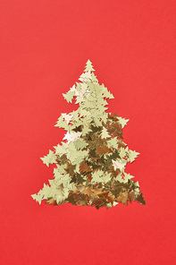 New Year decorative tree handmade from shiny small spruces on a red background, copy space. Greeting holiday card.