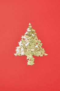 Creative Christmas decoration Tree from small shiny spruces on a red background with copy space. Greeting holiday card.