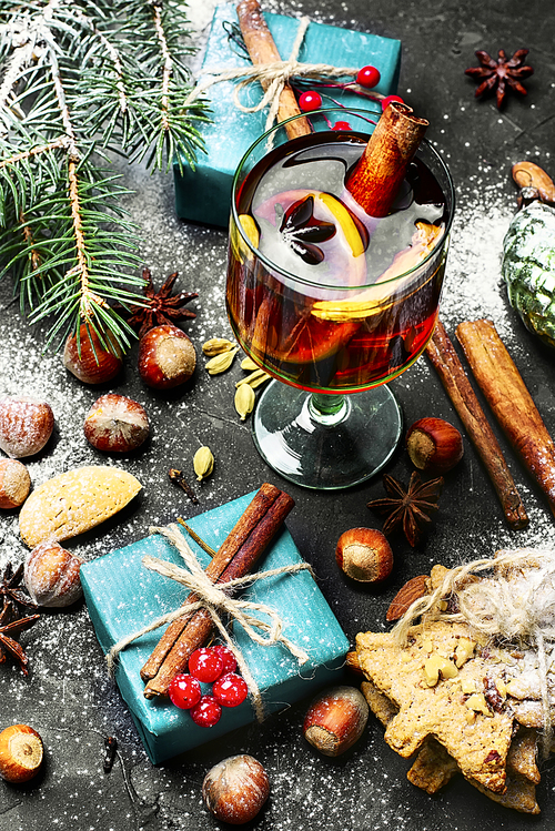 glass of mulled wine on dark Christmas background with boxes of Christmas gifts and spruce branch