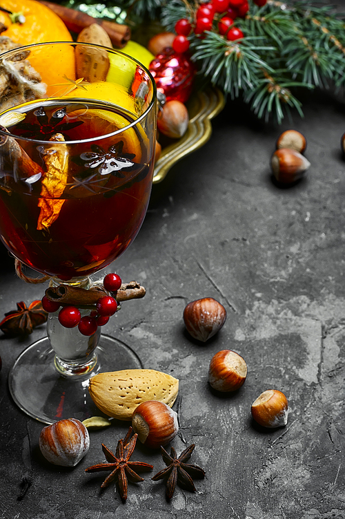 glass of mulled wine with spices on dark concrete background