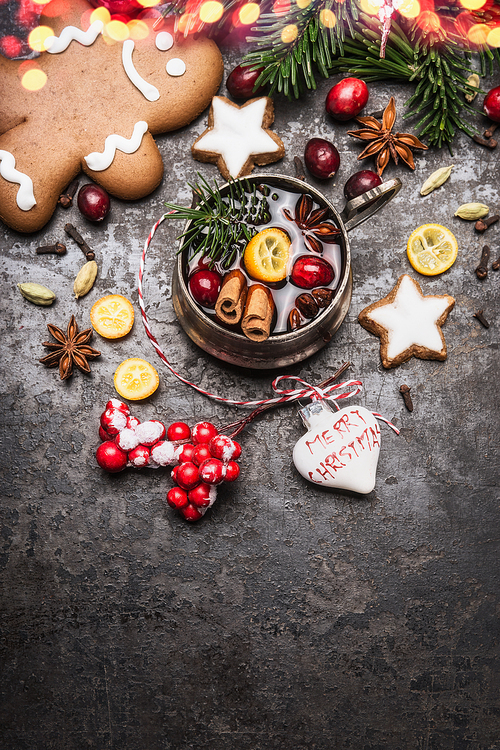Christmas mug of mulled wine with spices, cookies, gingerbread man and holiday decorations on dark vintage background, top view