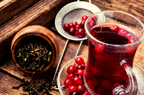 Cranberry tea in a glass cup on wooden table