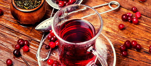 Cranberry tea in a glass cup on wooden table