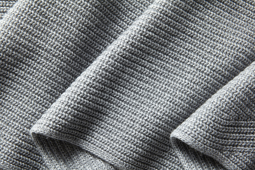 Gray wool knitted fabric folds. Natural draped knitted texture