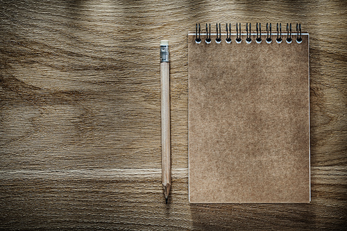 Pencil brown notebook on wooden board.
