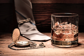 A conceptual image of aa glass of liquor, a pocket watch, and a neck tie.