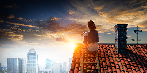 Young woman in casual clothes sitting on a house roof relaxed