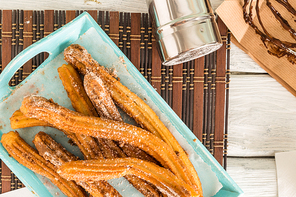 Traditional churros with hot chocolate dipping sauce on wooden counter top.