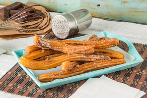 Traditional churros with hot chocolate dipping sauce on wooden counter top.