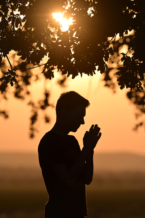 Closeup portrait young man praying hands clasped